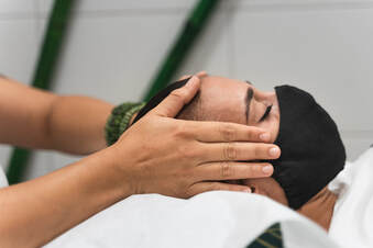Image of person wearing mask receiving neck and scalp massage.